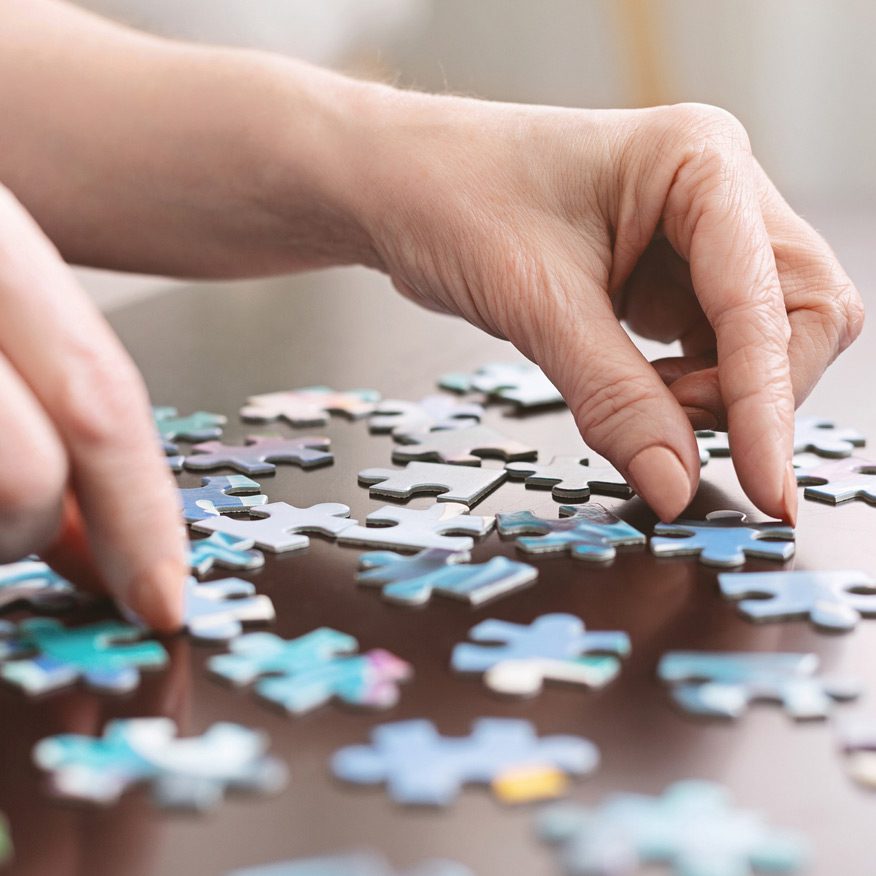 Elderly-woman’s-hands-putting-together-a-puzzle-as-part-of-memory-care