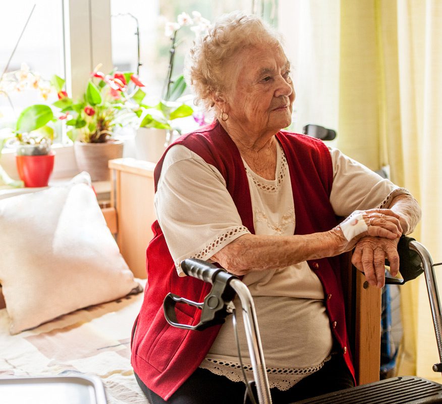 Senior-woman-sitting-on-her-bed-in-a-residential-care-home