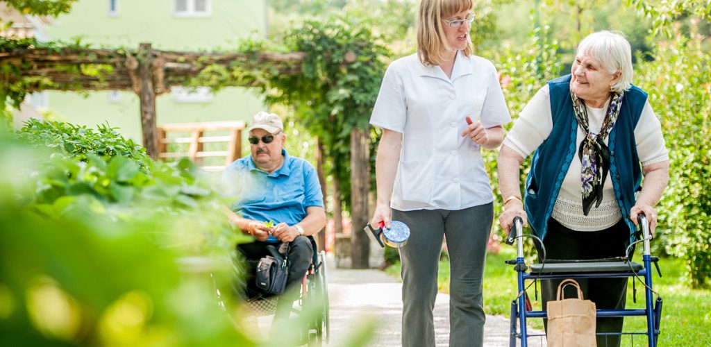 Senior-woman-walking-with-a-walker-in-the-outdoor-space-at-a-residential-care-home