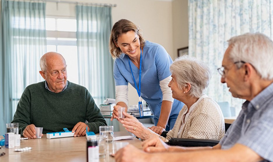 Female-nurse-administering-medication-to-group-of-seniors-at-assisted-living-in-The-Valley