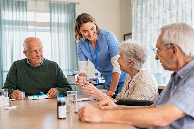 Female-nurse-administering-medication-to-group-of-seniors-at-assisted-living-in-The-Valley Female-nurse-administering-medication-to-group-of-seniors-at-assisted-living-in-The-Valley