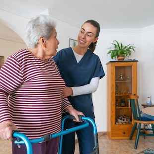 Home caregiver helping a senior woman using a walker at home Home caregiver helping a senior woman using a walker at home
