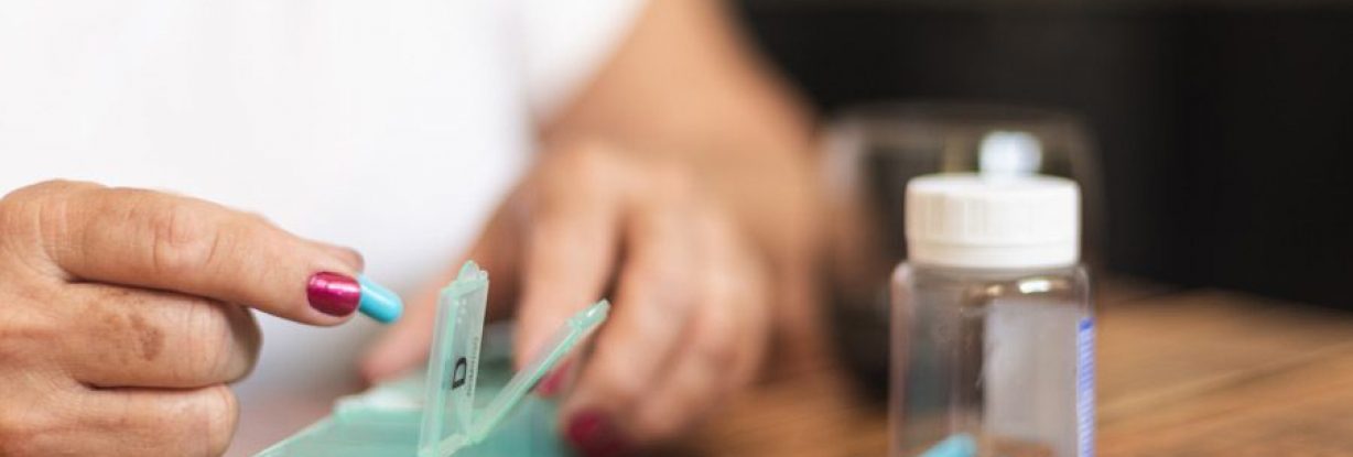 Senior-woman-placing-pills-into-pill-box